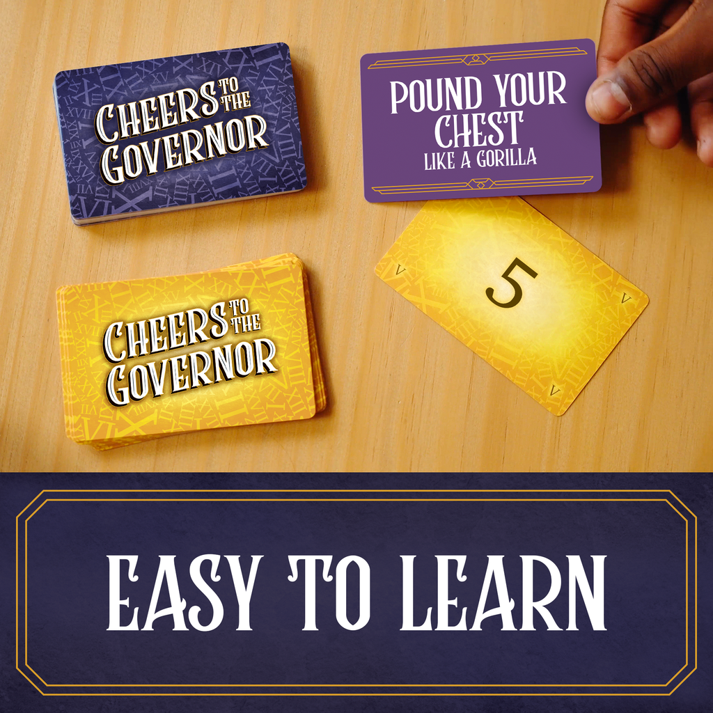 Card game with text on cards and a hand holding one, on a wooden surface. cheers to the governor. family game, party game, big groups.