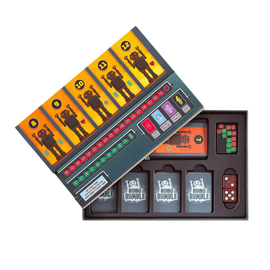 The Robo Rumble board game set shown open, featuring a dark gray control panel with colorful robot icons, several gray game cards, a green and red token grid, and a brown dice cup on a white background. game night family fun
