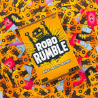 The board game 'Robo Rumble' box is shown at an angle, surrounded by a dense pile of colorful game cards featuring robot and tech designs. The box is bright orange with bold white and black text, and the background is a colorful mix of orange, yellow, pink, and blue cards. game night family fun