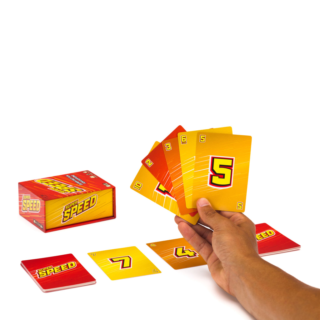 A hand holds a fan of yellow and orange Speed cards, with several cards laid out on a white background next to a red and yellow Speed game box. speed family fun card game